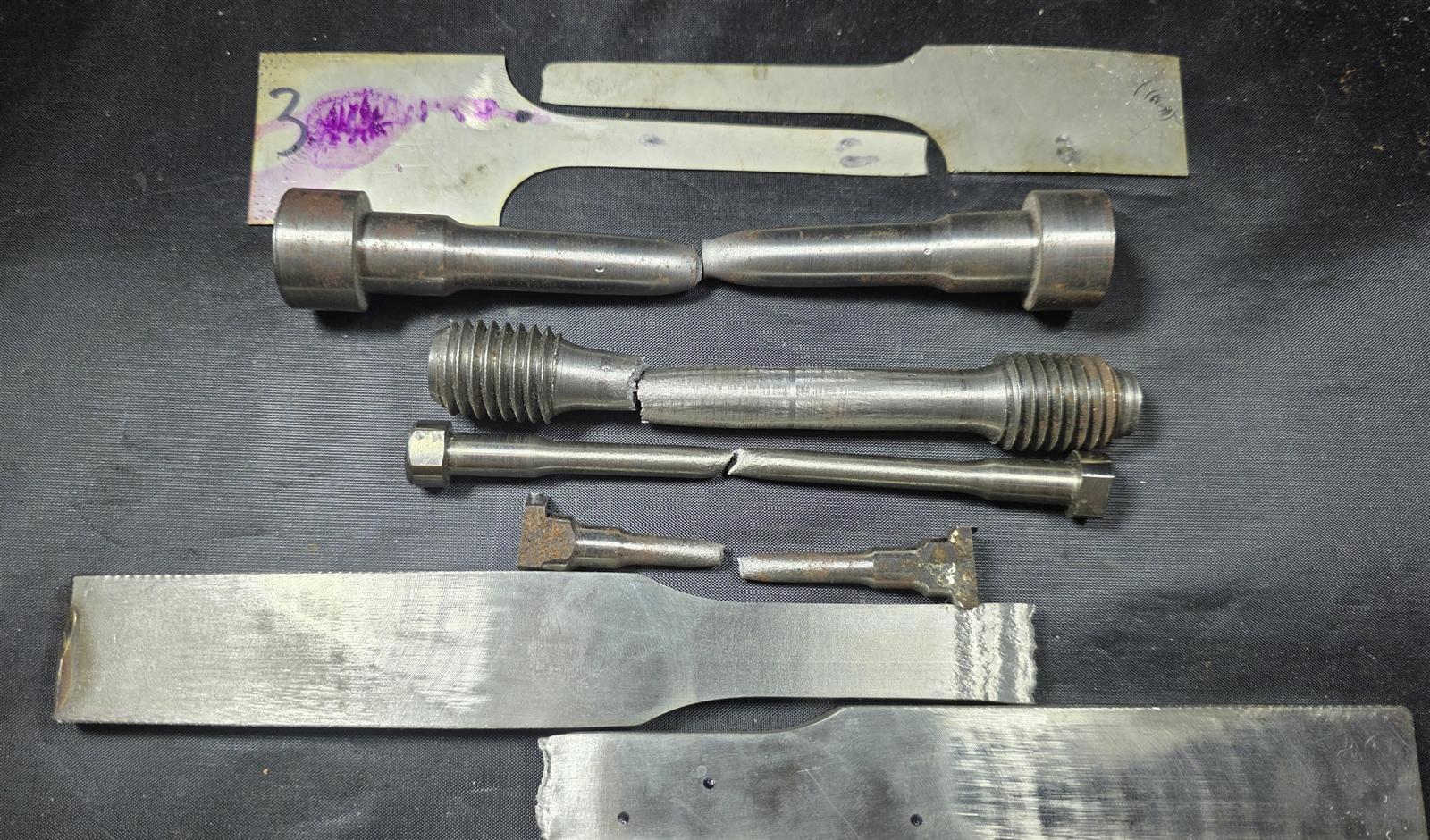 A family of tensile specimens pulled to failure: flat, round threaded, sub-size, and plate sections